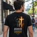 Man wearing a black t-shirt with a lion and cross design on a city street.