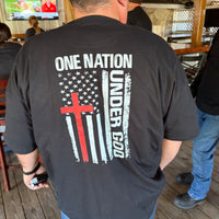 Person wearing a black t-shirt with a design featuring 'One Nation Under God' and an American flag.