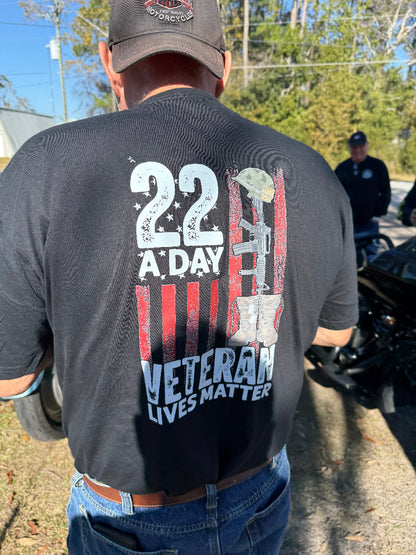 Person wearing a black t-shirt with '22 A Day Veteran Lives Matter' design outdoors.