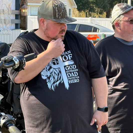 Two men standing next to a motorcycle with one wearing a black t-shirt with white text and graphics.