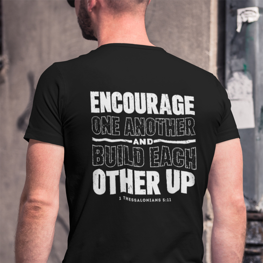 Person wearing a black t-shirt with motivational quote on the back, standing against an urban background.