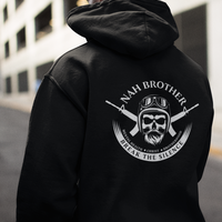 Person wearing a black hoodie with a logo and text on the back, standing in an urban setting.