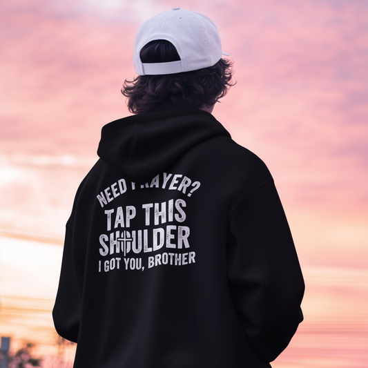 Person wearing a black hoodie with text on the back against a sunset sky.