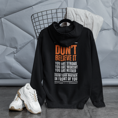 Black hoodie with text on a hanger against a textured gray wall.
