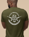 Man wearing a green t-shirt with a graphic design on the back against a beige background