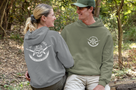 Two people sitting on a log in a forest wearing branded hoodies.