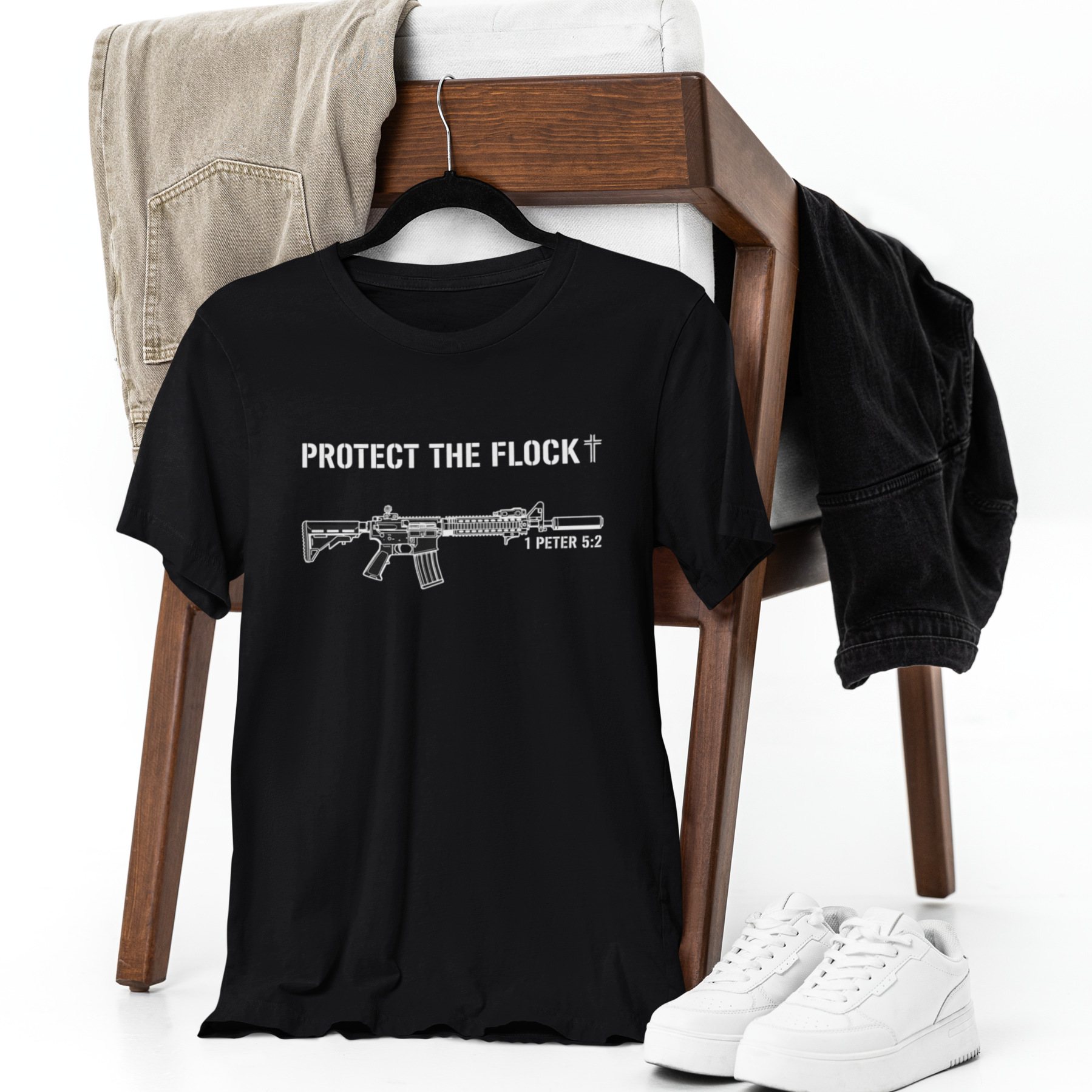 Black t-shirt with graphic design and text on a chair with shoes and pants.