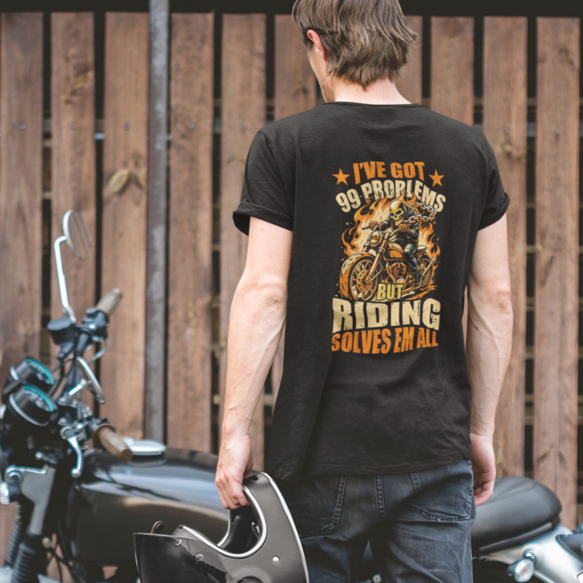 Man wearing a black t-shirt with text and graphics, standing next to a motorcycle.